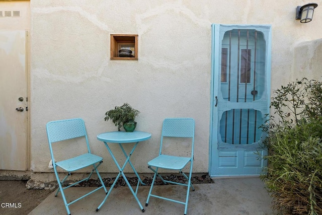 view of exterior entry with a patio area, visible vents, and stucco siding