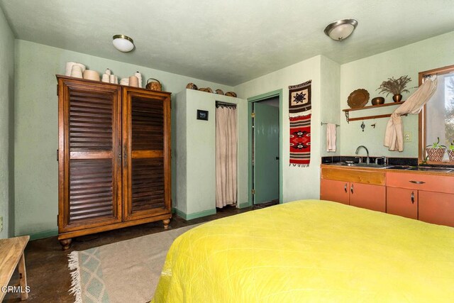 bedroom featuring concrete flooring, a sink, and baseboards