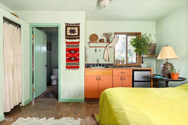 bedroom featuring finished concrete floors, a sink, and freestanding refrigerator