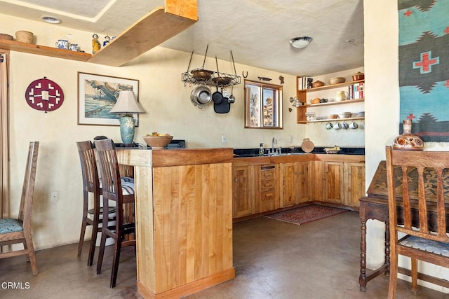 kitchen with a sink, finished concrete flooring, and open shelves