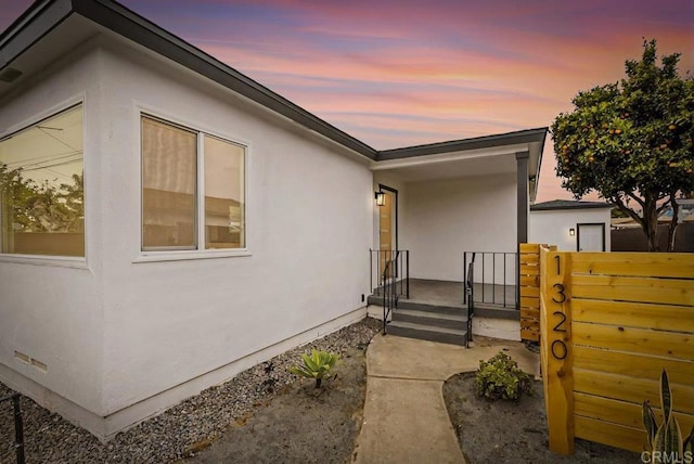 property exterior at dusk with crawl space and stucco siding