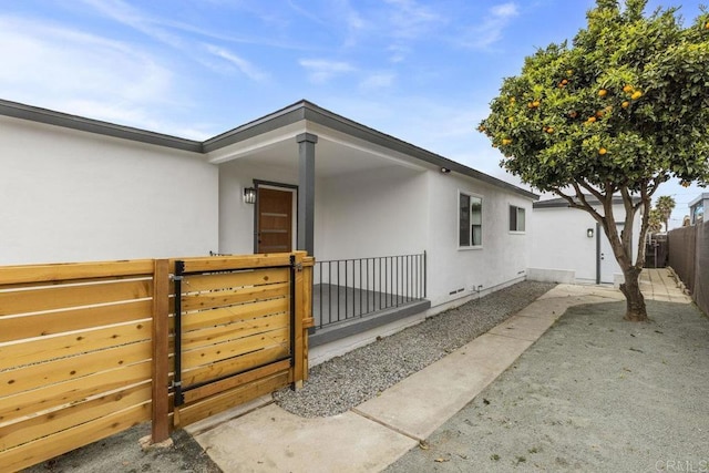 view of side of property with fence, a gate, and stucco siding