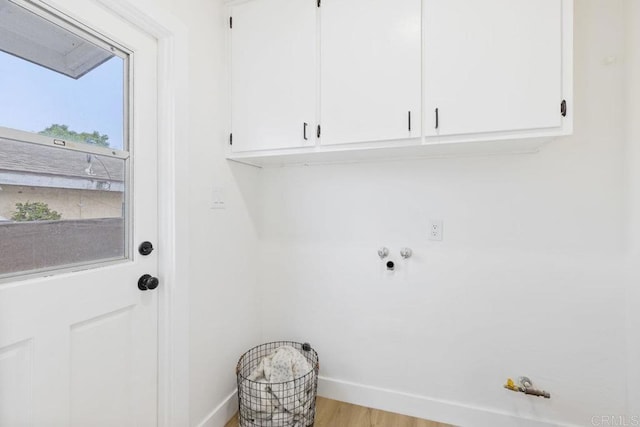 clothes washing area with wood finished floors, baseboards, washer hookup, and cabinet space