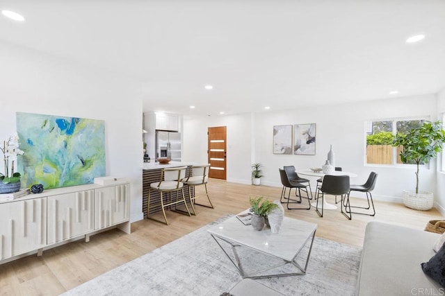 living area with recessed lighting, baseboards, and light wood-style flooring