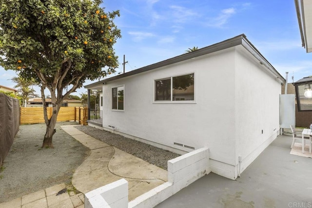 view of home's exterior featuring stucco siding, a patio, and fence