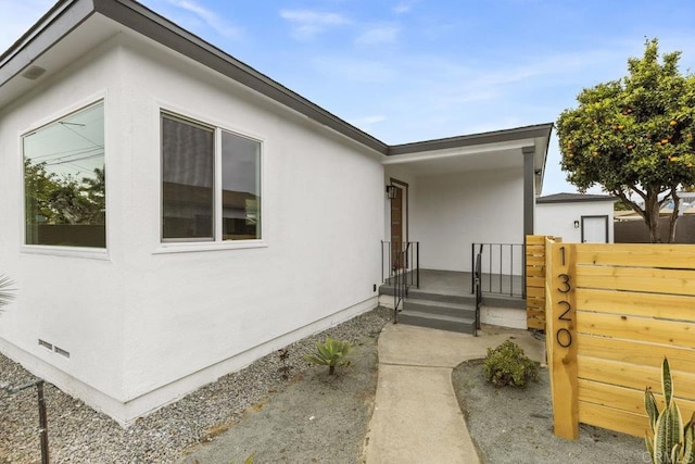 view of side of home with fence and stucco siding
