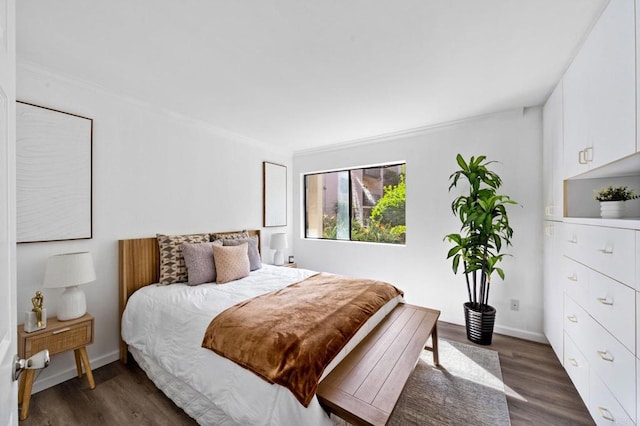 bedroom with baseboards, ornamental molding, and dark wood-type flooring