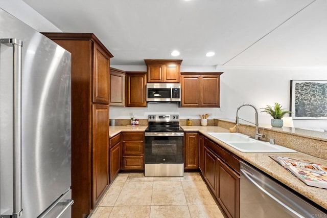 kitchen featuring light tile patterned floors, brown cabinetry, appliances with stainless steel finishes, a sink, and recessed lighting