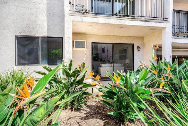 property entrance featuring a balcony and stucco siding