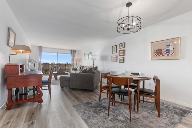 dining room with a chandelier, baseboards, and light wood-style flooring