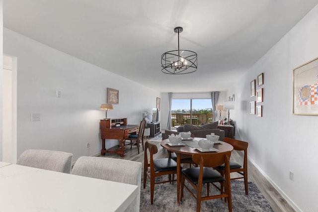 dining area with baseboards, an inviting chandelier, and dark wood-style flooring