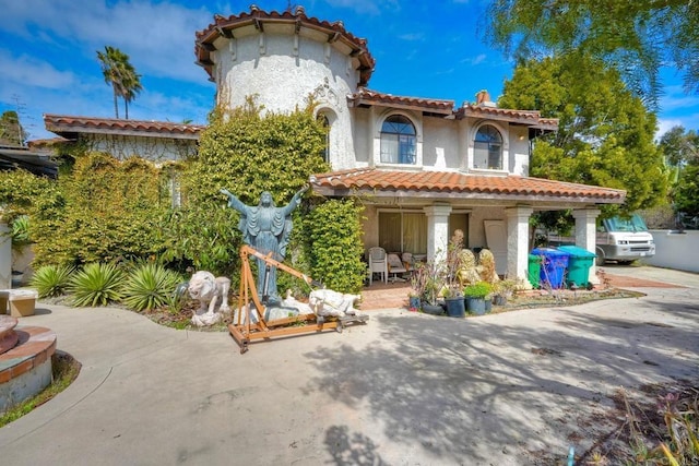 view of front of house with a patio area, a tile roof, and stucco siding