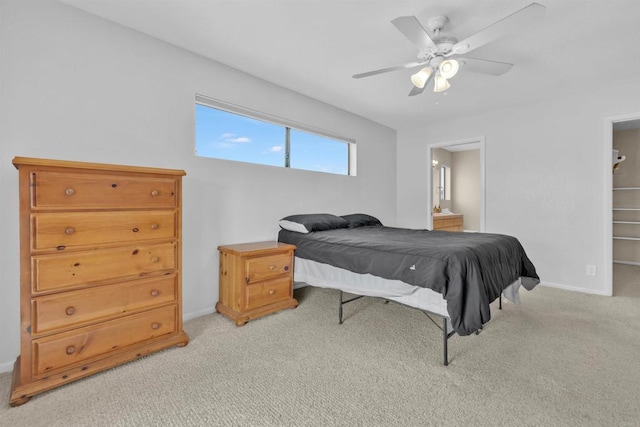 bedroom with baseboards, ensuite bathroom, a ceiling fan, and light colored carpet