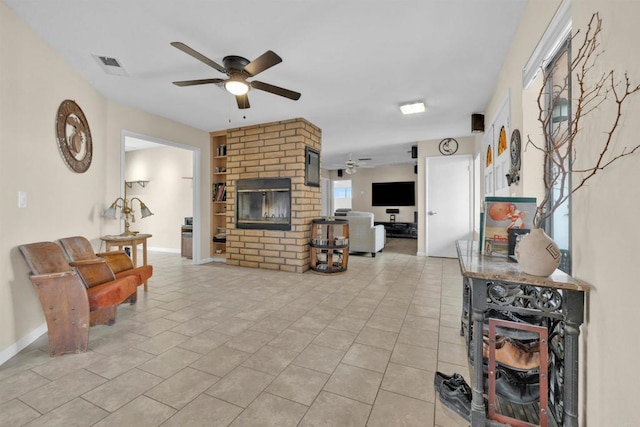 living area featuring light tile patterned floors, visible vents, baseboards, ceiling fan, and a fireplace