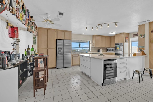 kitchen with stainless steel appliances, wine cooler, light tile patterned flooring, and light brown cabinetry