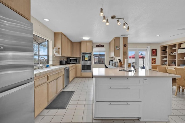 kitchen featuring light brown cabinets, stainless steel appliances, a sink, and light tile patterned flooring