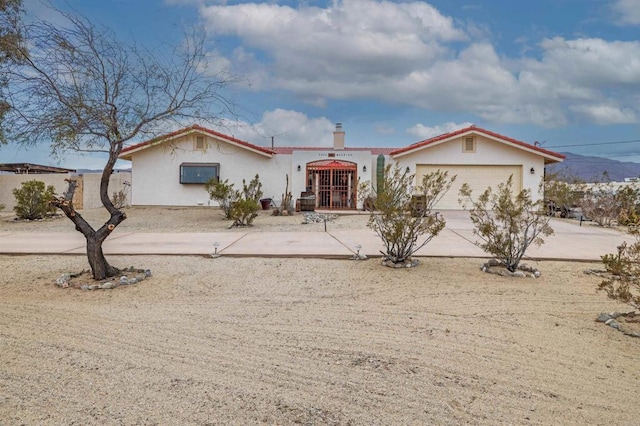 mediterranean / spanish-style home featuring a garage, concrete driveway, a chimney, and stucco siding