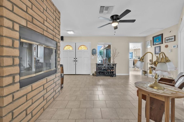 tiled foyer entrance with ceiling fan, visible vents, and baseboards