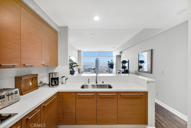 kitchen featuring dark wood-style floors, modern cabinets, a peninsula, light countertops, and a sink