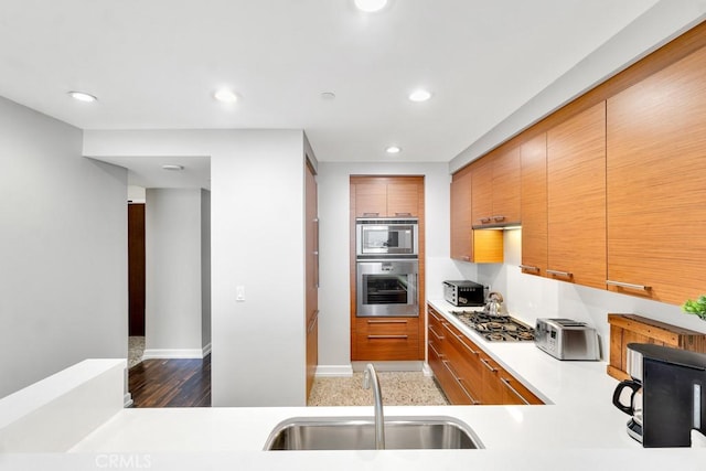 kitchen with light countertops, appliances with stainless steel finishes, a sink, and recessed lighting