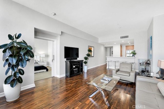 living area with wood finished floors, visible vents, and baseboards