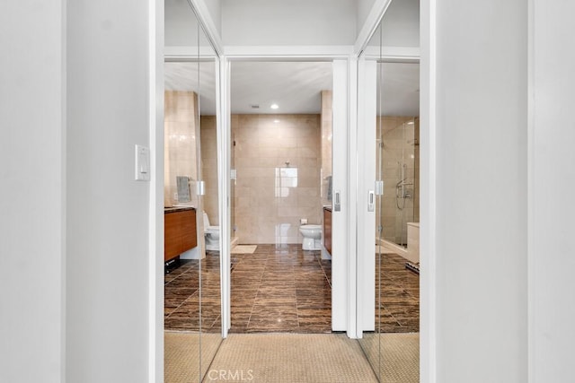 bathroom featuring toilet, a shower stall, tile walls, and recessed lighting