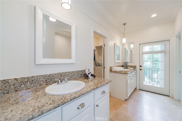 bathroom with crown molding, two vanities, and a sink