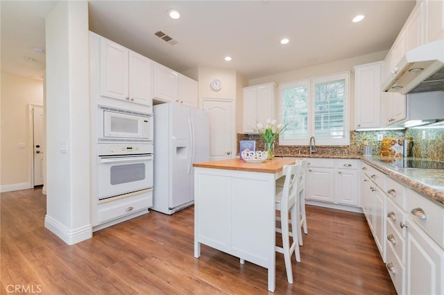 kitchen featuring white appliances, a sink, white cabinetry, visible vents, and tasteful backsplash