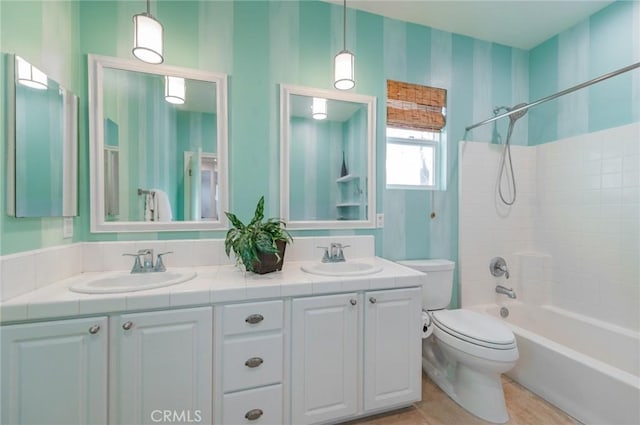 bathroom with toilet, double vanity,  shower combination, and a sink