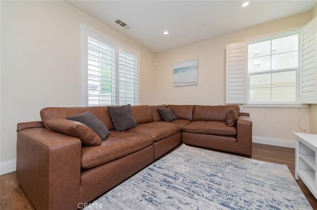 living room with recessed lighting, visible vents, baseboards, and wood finished floors