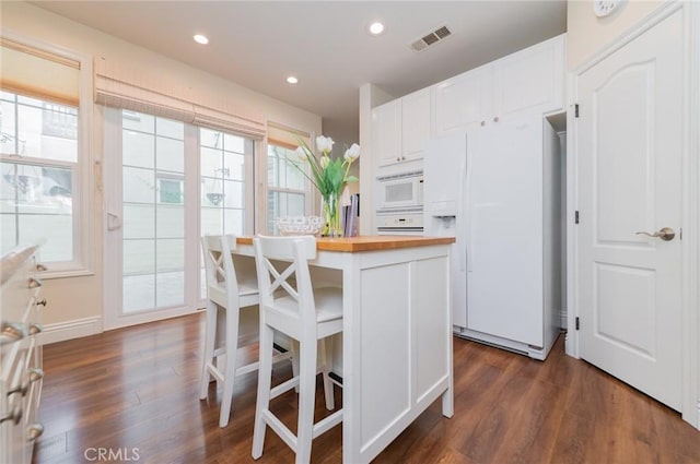 kitchen featuring visible vents, butcher block counters, a wealth of natural light, and white appliances