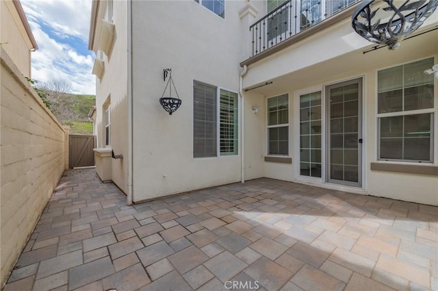 view of patio with fence and a balcony