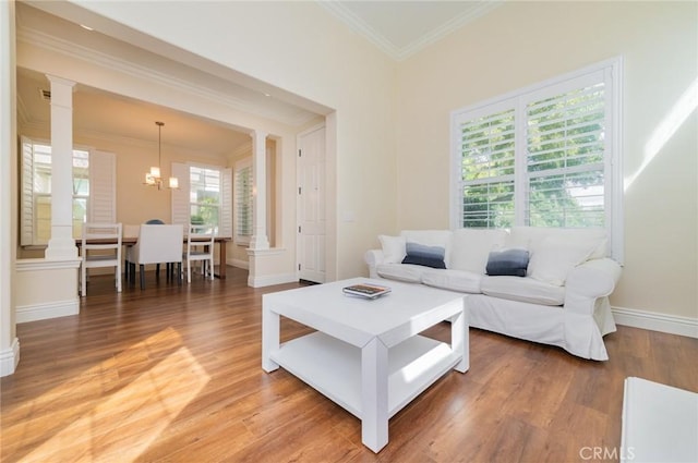 living room with ornamental molding, light wood finished floors, decorative columns, and a healthy amount of sunlight