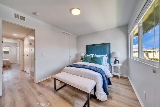 bedroom featuring baseboards, a closet, visible vents, and light wood-style floors