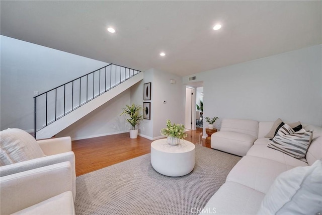 living room featuring baseboards, visible vents, stairway, wood finished floors, and recessed lighting