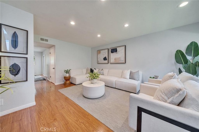 living area with baseboards, light wood-type flooring, visible vents, and recessed lighting