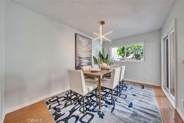 dining area featuring a notable chandelier, baseboards, and wood finished floors