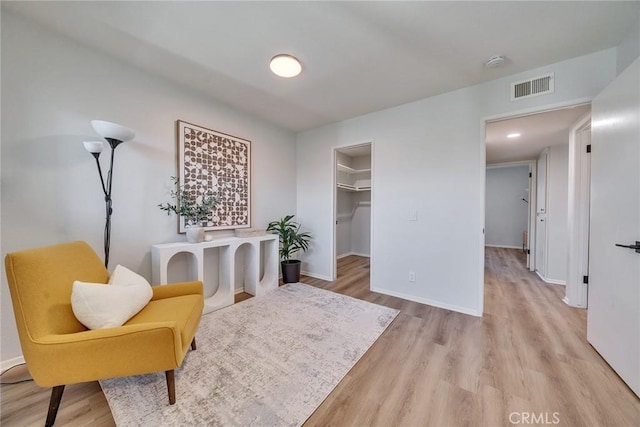 sitting room featuring light wood-style flooring, visible vents, and baseboards