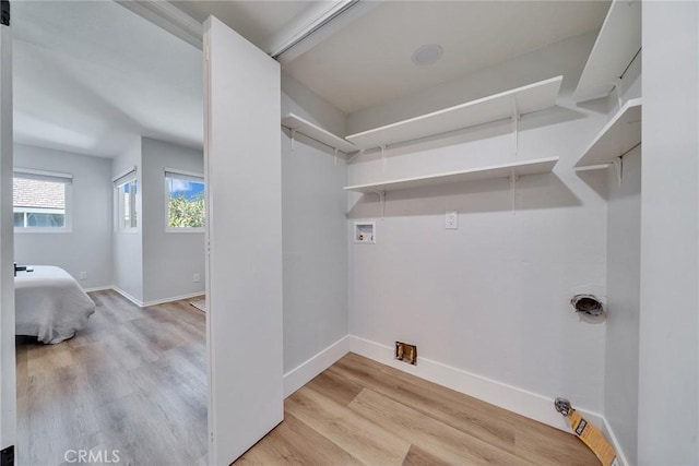 clothes washing area with washer hookup, laundry area, baseboards, and wood finished floors