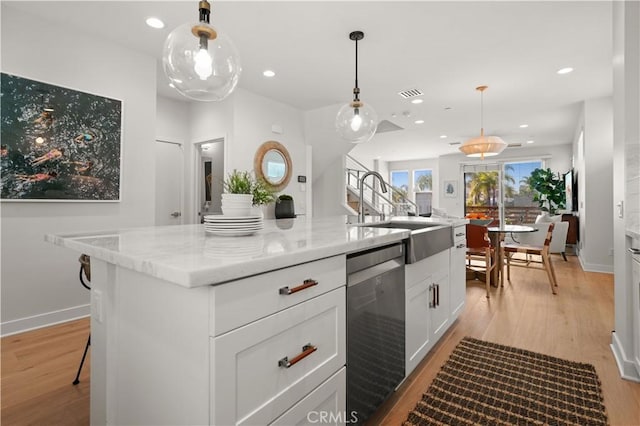 kitchen featuring stainless steel dishwasher, light wood-style flooring, visible vents, and a sink