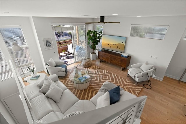 living room featuring baseboards, light wood-type flooring, and ceiling fan