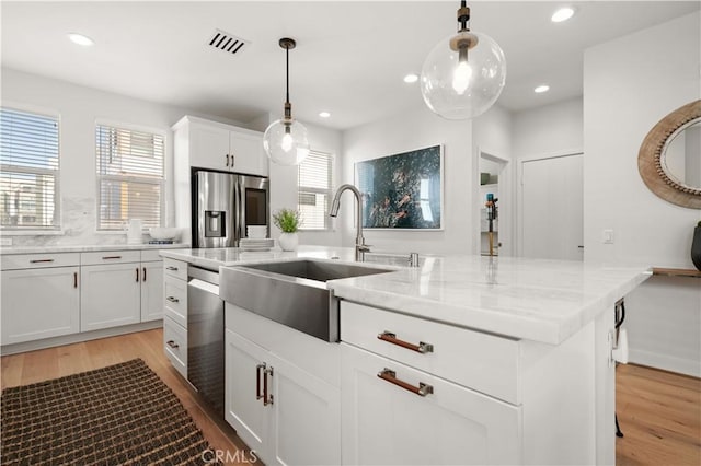 kitchen with a sink, light wood-type flooring, visible vents, and stainless steel appliances