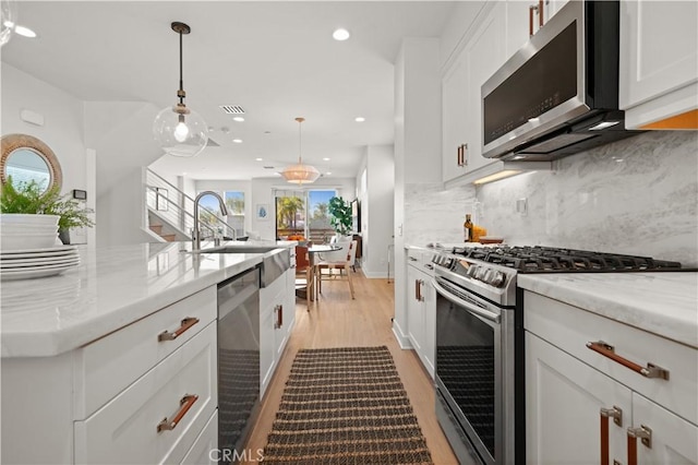 kitchen featuring decorative backsplash, white cabinets, stainless steel appliances, and a sink