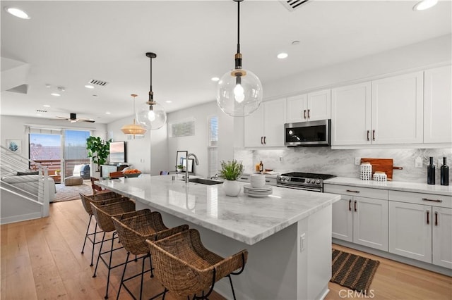 kitchen featuring visible vents, appliances with stainless steel finishes, decorative backsplash, and a sink