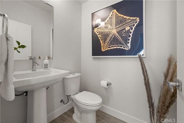 bathroom featuring baseboards, toilet, and wood finished floors