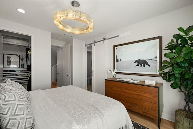 bedroom with recessed lighting, a barn door, and wood finished floors