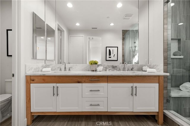 full bathroom featuring a sink, toilet, a stall shower, and double vanity