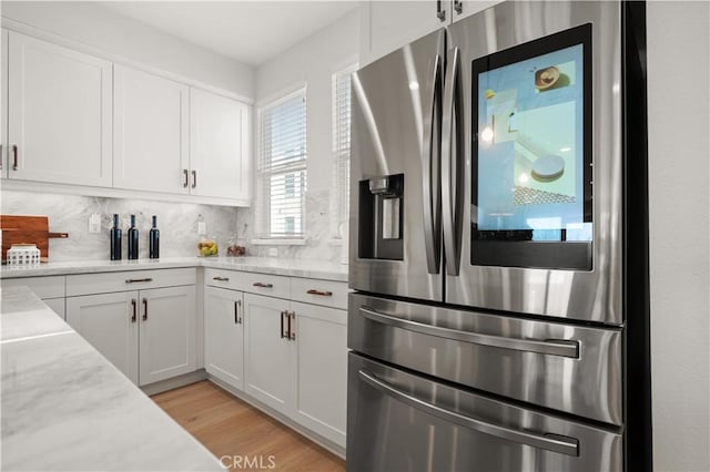 kitchen with tasteful backsplash, stainless steel fridge with ice dispenser, light stone counters, light wood-style floors, and white cabinetry