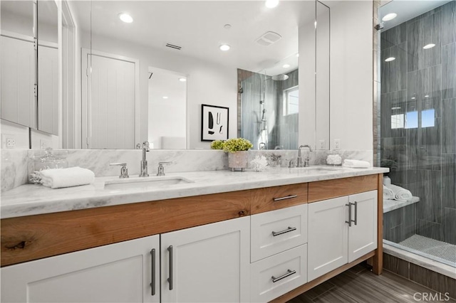 full bathroom featuring double vanity, a stall shower, and a sink