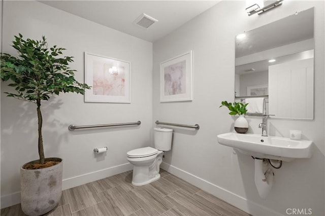 bathroom with wood finish floors, visible vents, baseboards, and toilet